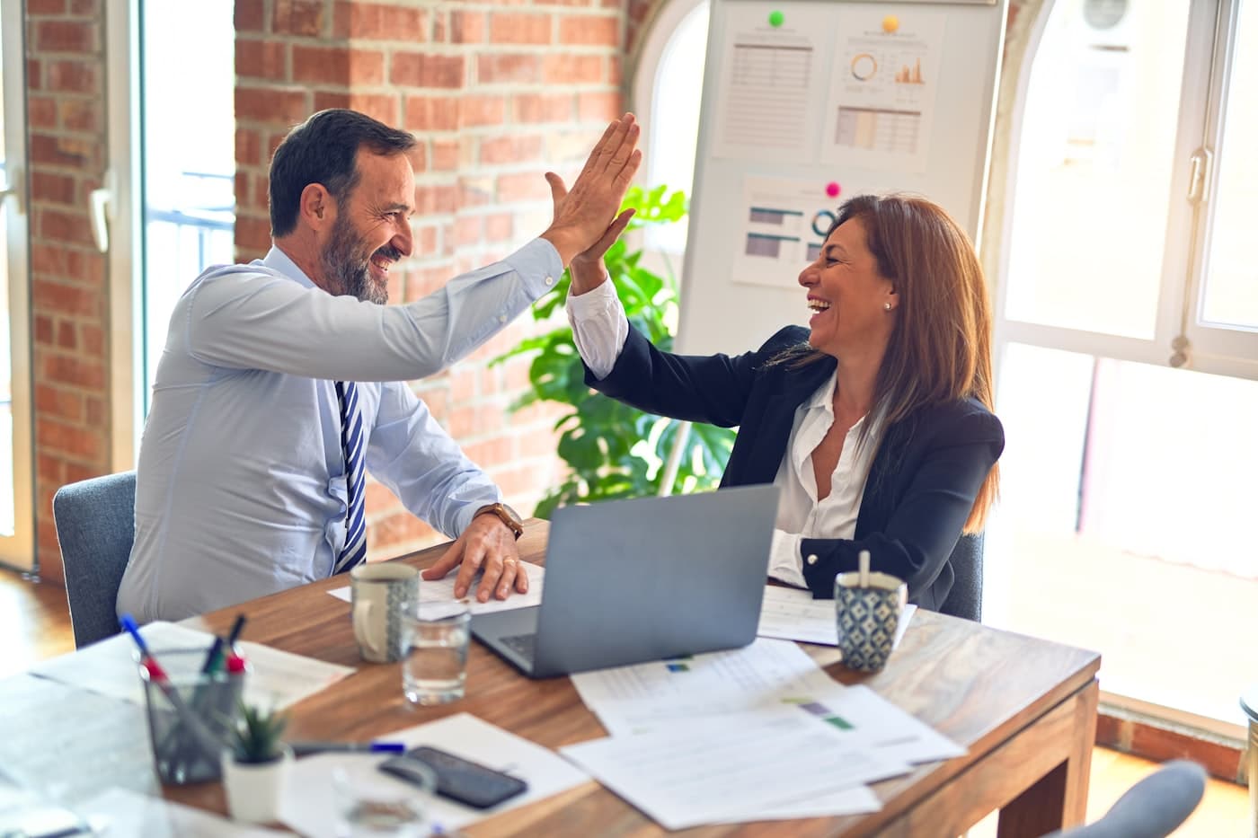 Two colleagues celebrating a result together at a desk