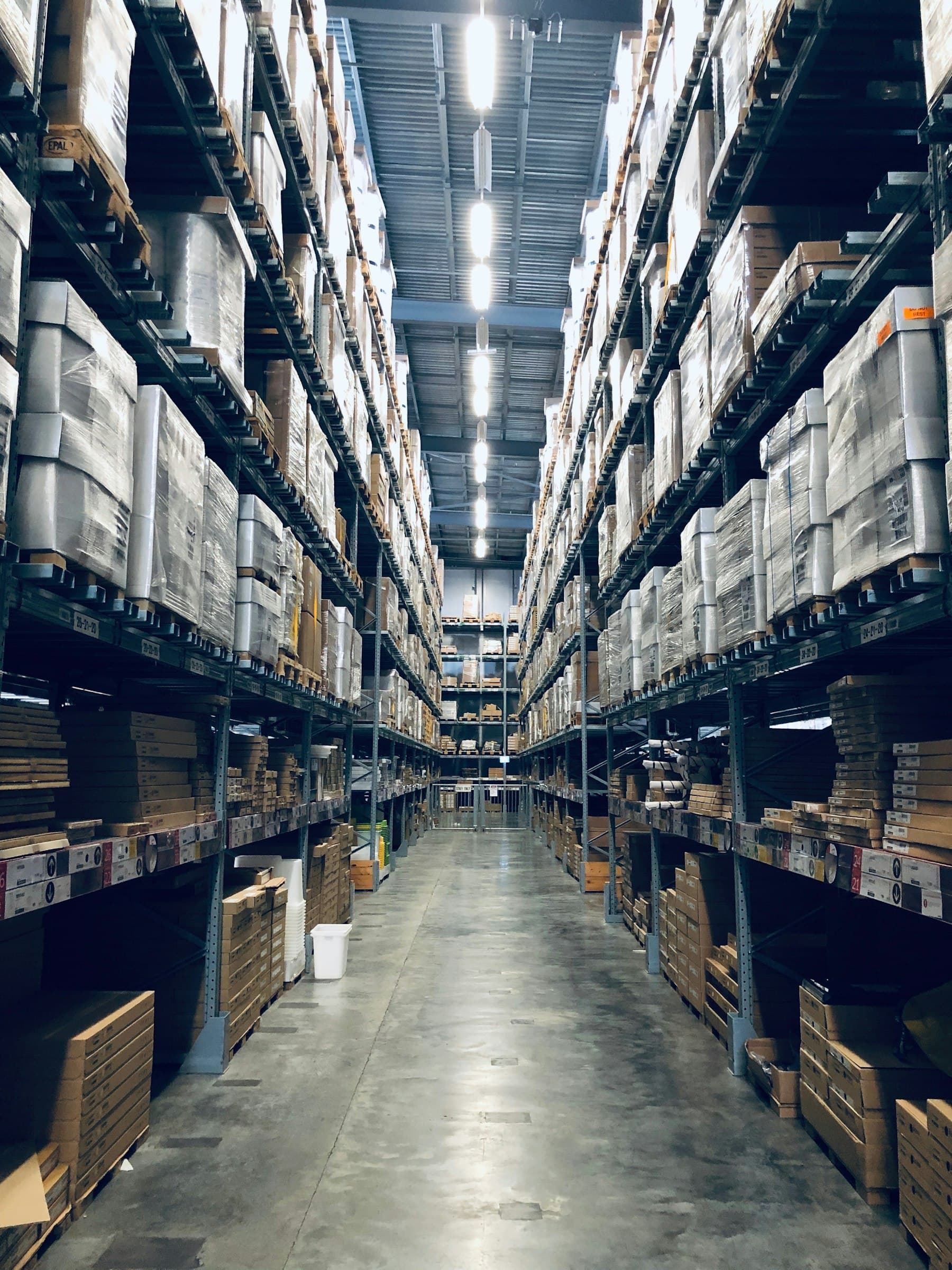 Warehouse aisle of stocked pallet racking running into the distance